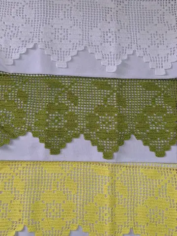 Três barrados de crochê filet com flores, nas cores branca, verde e amarela, aplicados em tecido